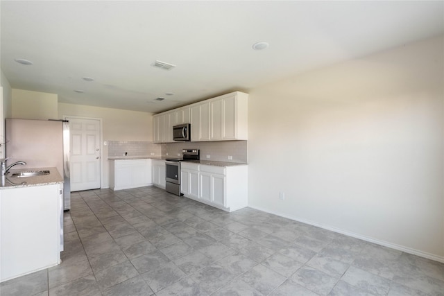 kitchen with visible vents, a sink, decorative backsplash, stainless steel appliances, and white cabinetry