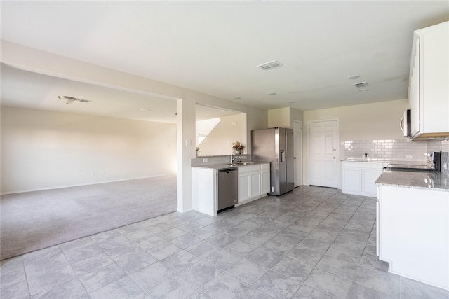 kitchen featuring visible vents, backsplash, open floor plan, light carpet, and appliances with stainless steel finishes