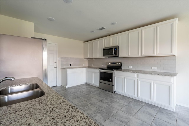 kitchen featuring visible vents, decorative backsplash, appliances with stainless steel finishes, white cabinetry, and a sink