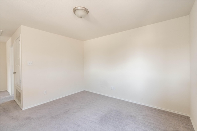 unfurnished room featuring baseboards and light carpet