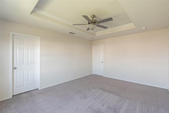 empty room featuring visible vents, a ceiling fan, a tray ceiling, and ornamental molding