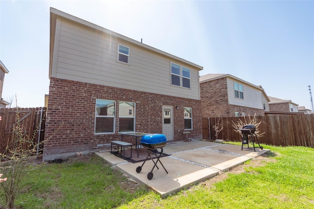 rear view of property featuring a yard, a patio, brick siding, and a fenced backyard
