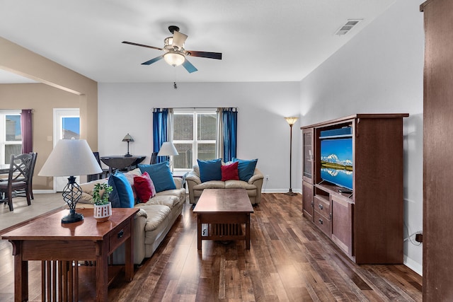 living area with dark wood-type flooring, plenty of natural light, visible vents, and ceiling fan