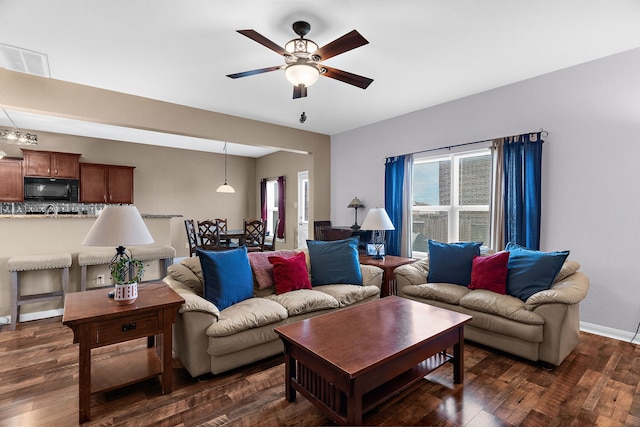 living room featuring dark wood finished floors, visible vents, baseboards, and ceiling fan