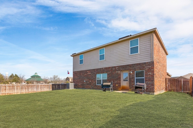 back of property featuring brick siding, a fenced backyard, and a lawn