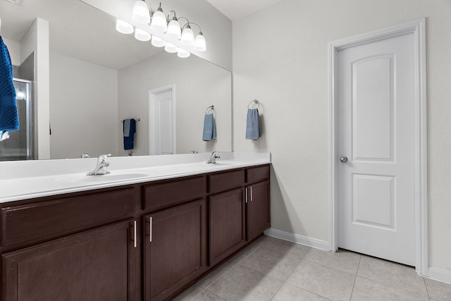 full bath with baseboards, double vanity, a stall shower, tile patterned floors, and a sink