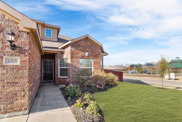 property entrance featuring a yard, fence, and brick siding