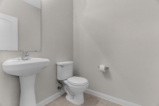 bathroom with tile patterned floors, toilet, baseboards, and a sink