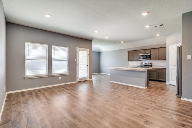 kitchen featuring light wood-type flooring, visible vents, open floor plan, appliances with stainless steel finishes, and light countertops