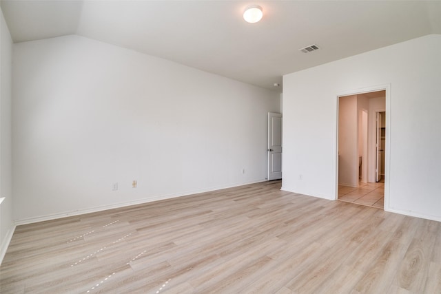 unfurnished room featuring lofted ceiling, light wood-style flooring, baseboards, and visible vents