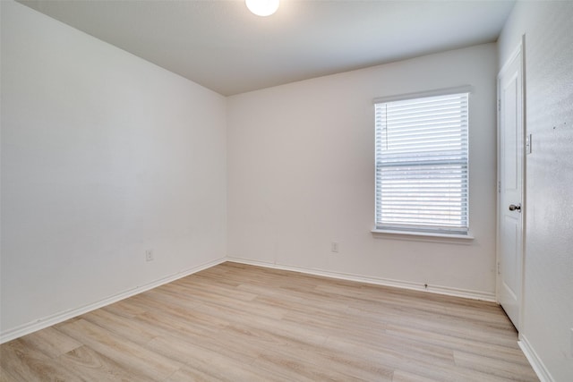 empty room featuring baseboards and light wood finished floors
