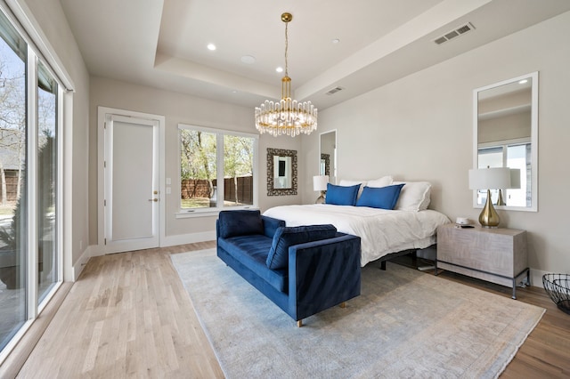 bedroom featuring light wood finished floors, a chandelier, access to exterior, baseboards, and a raised ceiling