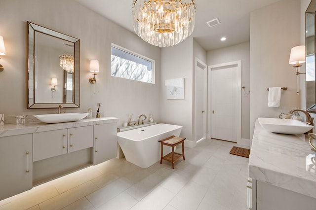 bathroom with a chandelier, a freestanding bath, two vanities, baseboards, and recessed lighting