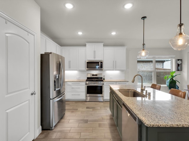 kitchen with recessed lighting, a sink, decorative backsplash, stainless steel appliances, and a kitchen island with sink