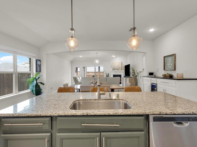 kitchen featuring a healthy amount of sunlight, stainless steel dishwasher, light stone counters, and open floor plan