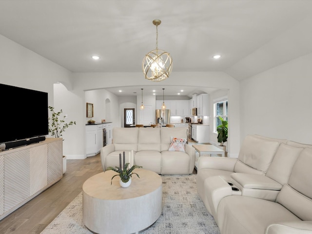 living room with arched walkways, recessed lighting, a notable chandelier, and light wood-type flooring