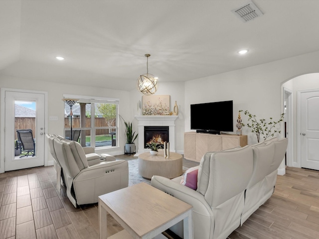 living room featuring light wood finished floors, visible vents, arched walkways, and recessed lighting