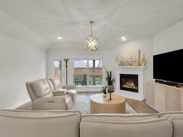 living area with baseboards, a glass covered fireplace, recessed lighting, and wood finished floors