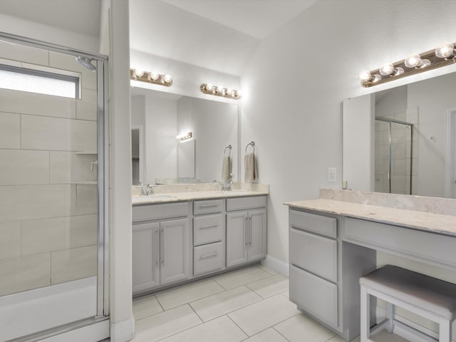 full bath featuring a stall shower, tile patterned floors, double vanity, and a sink