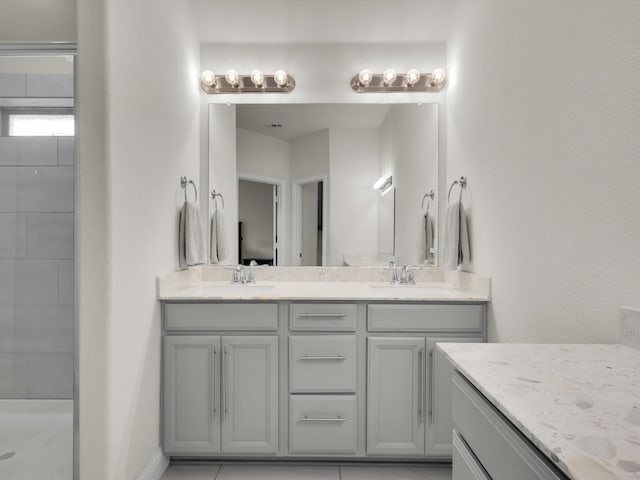 full bath with double vanity, a tile shower, and a sink