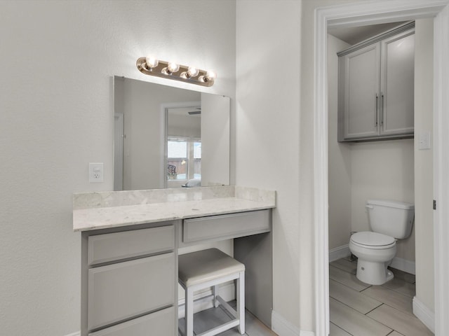 bathroom with baseboards, vanity, and toilet