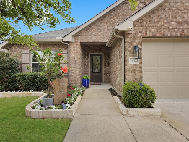 doorway to property featuring an attached garage, a shingled roof, and brick siding