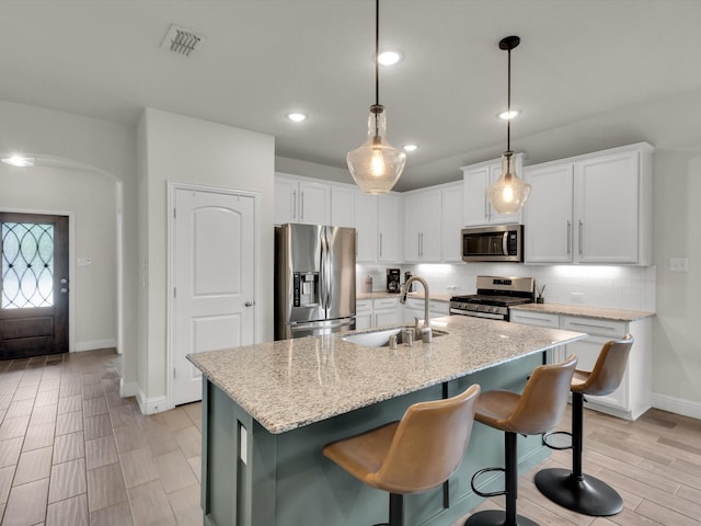 kitchen featuring a sink, backsplash, white cabinets, baseboards, and appliances with stainless steel finishes