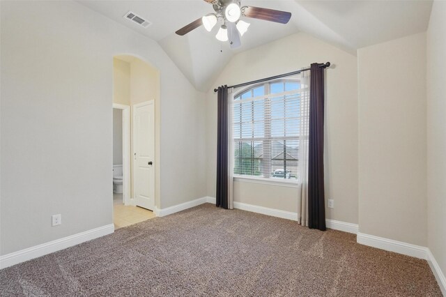 empty room with a ceiling fan, light colored carpet, visible vents, baseboards, and lofted ceiling