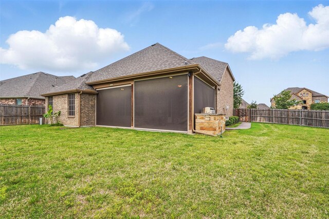 rear view of house featuring a sunroom, a fenced backyard, and a yard
