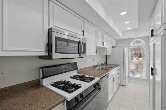 kitchen featuring a sink, white appliances, white cabinetry, and recessed lighting