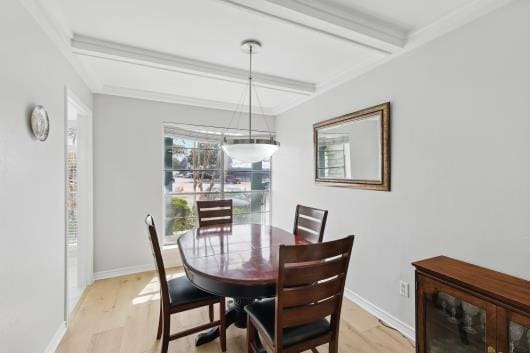 dining area featuring light wood-style floors, baseboards, and beamed ceiling