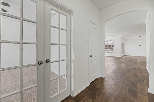 hall featuring arched walkways and dark wood-style flooring