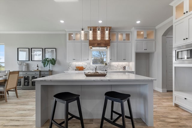 kitchen with stainless steel microwave, light stone countertops, a kitchen island, and ornamental molding