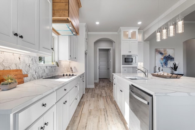 kitchen with backsplash, ornamental molding, arched walkways, stainless steel appliances, and a sink
