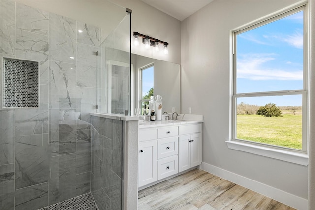 full bath with vanity, wood finished floors, baseboards, and a walk in shower