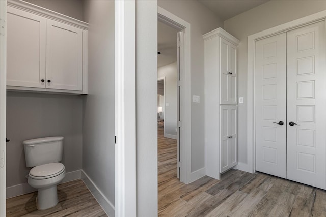 bathroom with toilet, baseboards, and wood finished floors