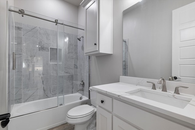 bathroom with vanity, toilet, wood finished floors, and bath / shower combo with glass door