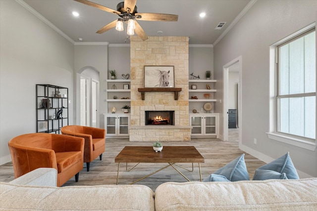 living room featuring visible vents, light wood-style flooring, a ceiling fan, arched walkways, and crown molding