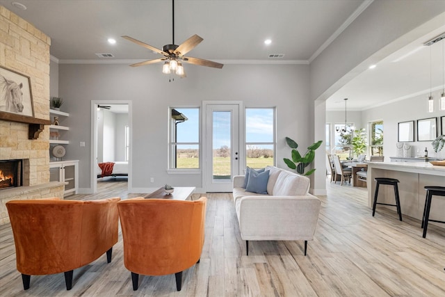 living area featuring a stone fireplace, visible vents, light wood-style floors, and ornamental molding
