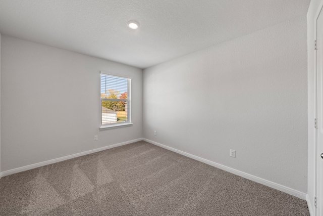 carpeted empty room with a textured ceiling and baseboards