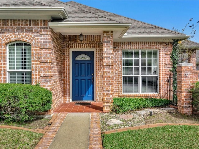 property entrance with brick siding and a shingled roof