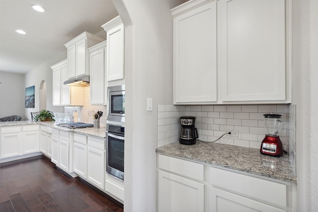 140 Dogwood Dr, Krugerville, TX 76227 - kitchen featuring dark wood-type flooring, under cabinet range hood, stainless steel appliances, arched walkways, and white cabinets