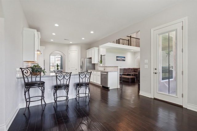 140 Dogwood Dr, Krugerville, TX 76227 - kitchen with a breakfast bar area, dark wood-style floors, a peninsula, stainless steel appliances, and white cabinetry