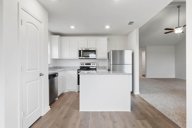 kitchen with a kitchen island, ceiling fan, a sink, appliances with stainless steel finishes, and white cabinetry