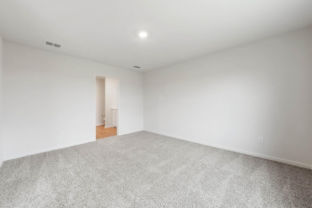 empty room with light colored carpet, visible vents, and baseboards