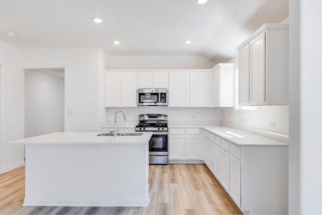 kitchen featuring light wood-style floors, a kitchen island with sink, light countertops, a sink, and stainless steel appliances