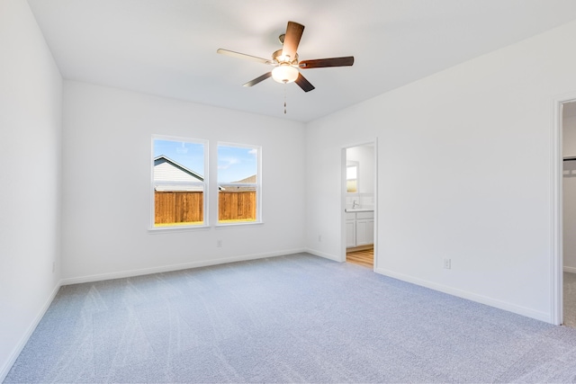 unfurnished room with baseboards, a ceiling fan, and light colored carpet