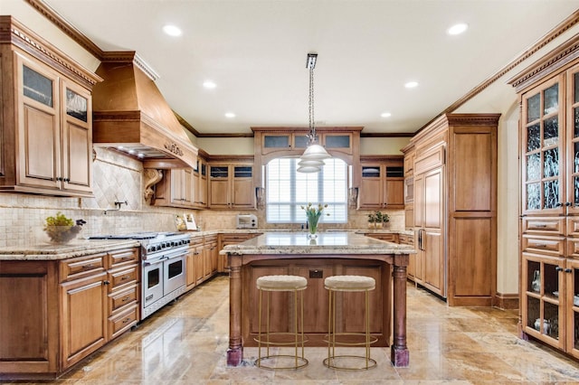 kitchen with a kitchen island, glass insert cabinets, light stone countertops, premium range hood, and premium appliances
