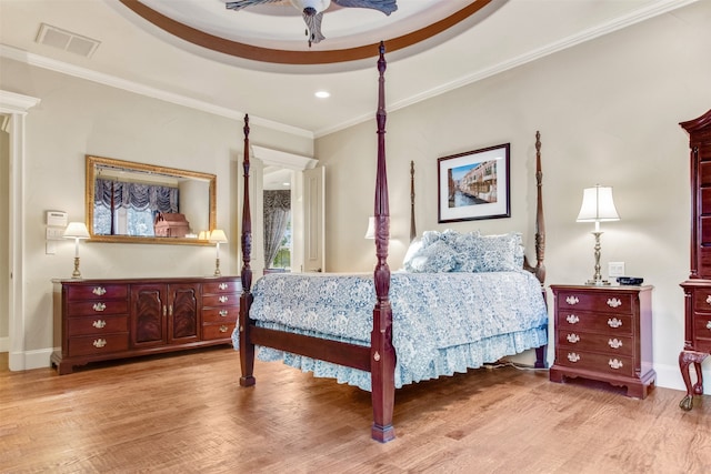 bedroom featuring visible vents, crown molding, baseboards, wood finished floors, and a raised ceiling