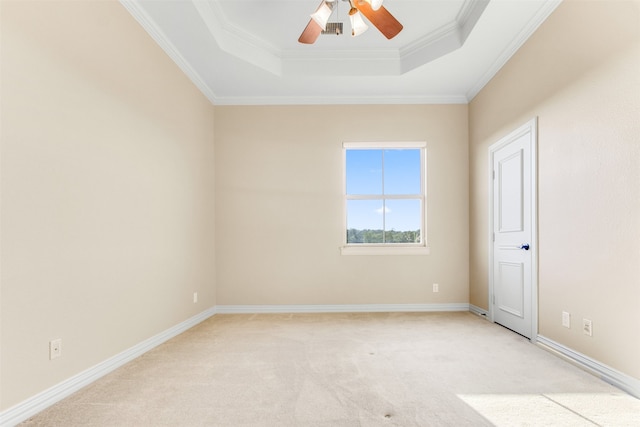 spare room with a ceiling fan, baseboards, crown molding, a raised ceiling, and light colored carpet